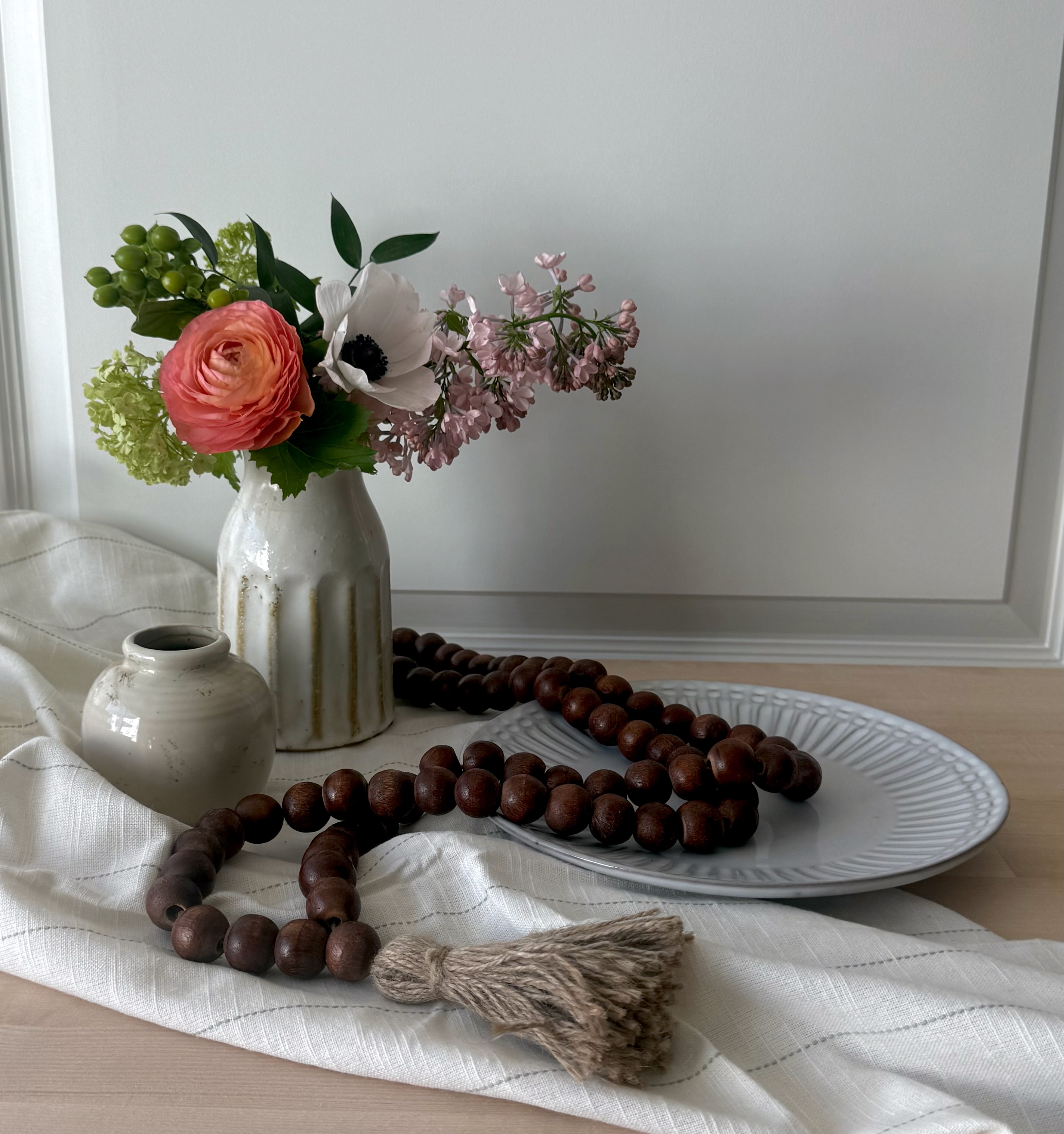Ranunculus and lilac arrangement with beads on linen
