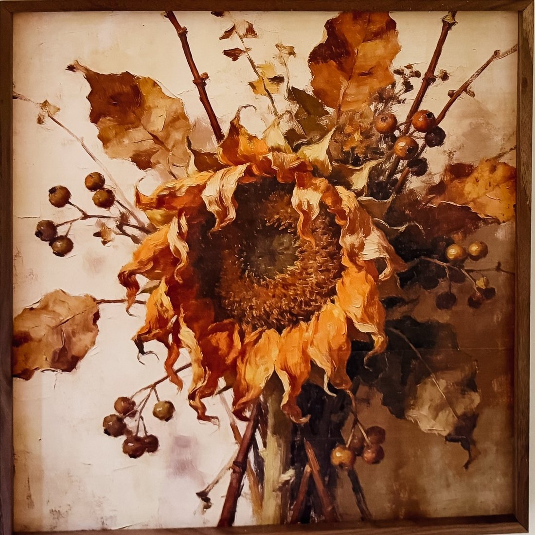 A framed painting of a single sunflower going over, in amber and brown, with berries and dried leaves.