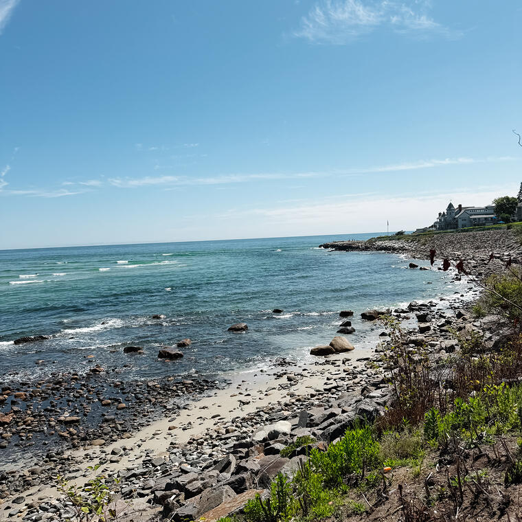 A rocky New England coastline under a clear sky.