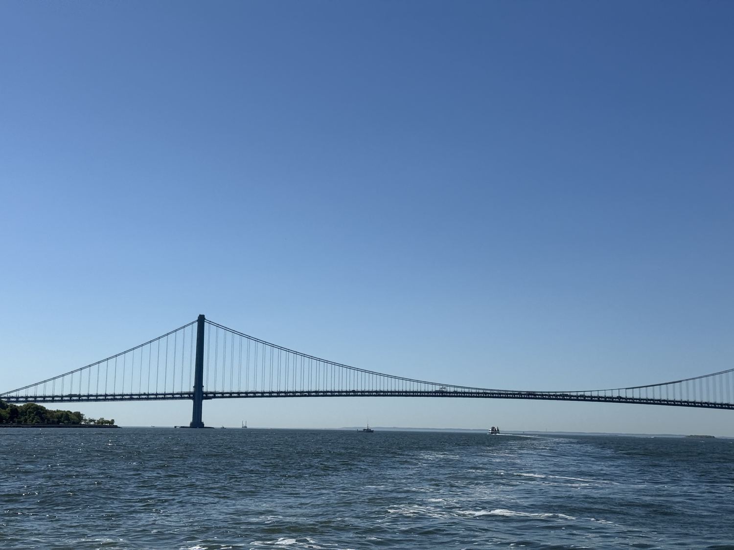 The Verrazzano Bridge stretching across a wide blue sky over the water.