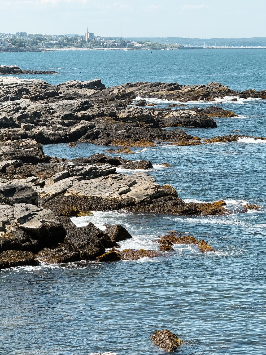 Waves breaking over the ledge, the far shore visible across the water.