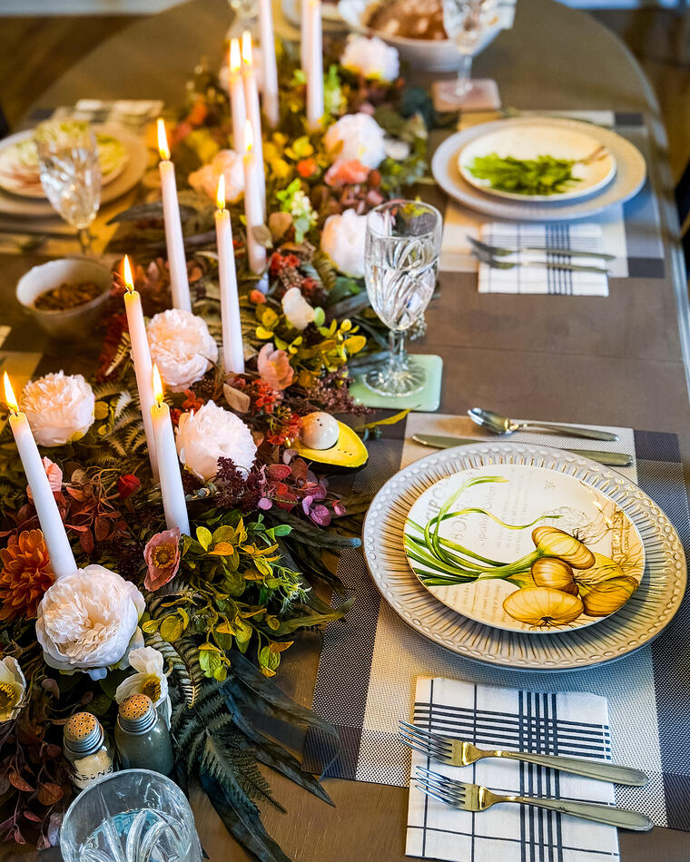 A long dining table set for eight, tapered candles down the centre and an autumn floral runner.