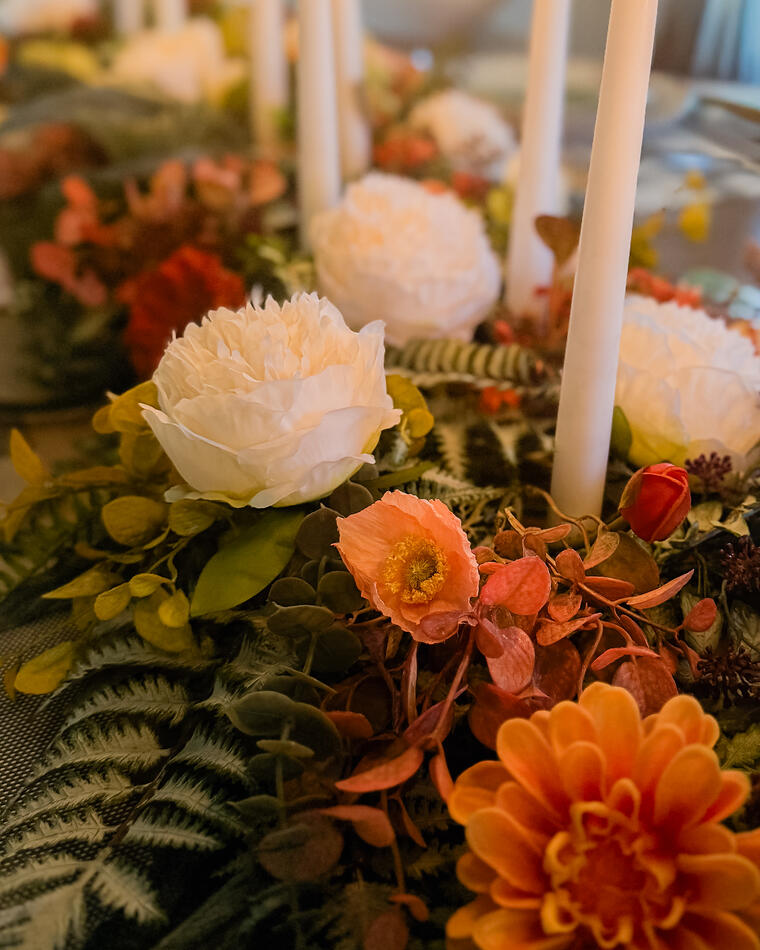 A close view of the centrepiece: dahlias, garden roses, fern and lit tapers.