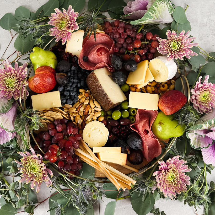 An overhead grazing board ringed with eucalyptus and pink chrysanthemum on pale stone.